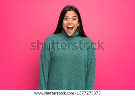 Young Colombian girl with green sweater with surprise facial expression