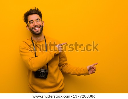 Young photographer man pointing to the side with finger