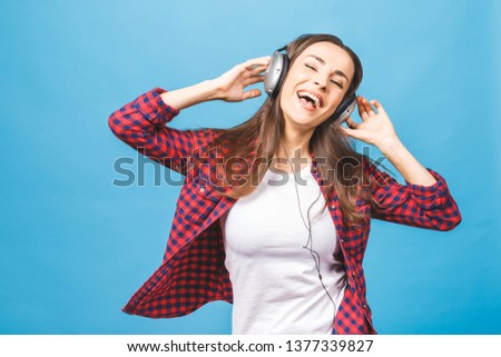 Woman with headphones listening music. Music teenager girl dancing against isolated blue background.