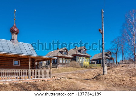 Country landscape with a rural road and a small chapel. Typical  Russian village street with wooden rural houses