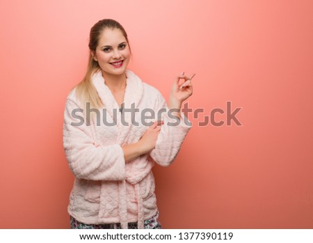 Young russian woman wearing pajama pointing to the side with finger