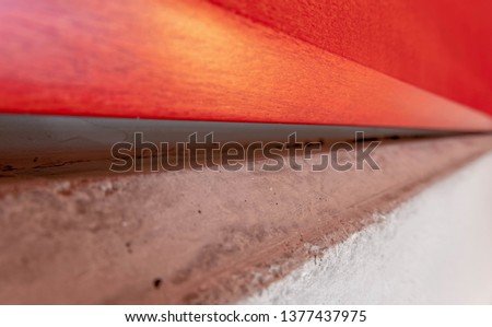 red lacquered wood and raw cement surface close up abstract background, extreme perspective and blur