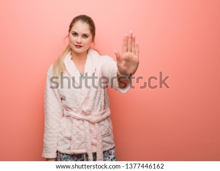 Young russian woman wearing pajama putting hand in front