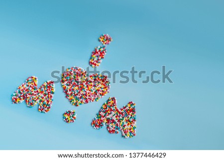 The inscription "mom" made by multi-colored candies on a blue background to the Mother's Day for greeting card / poster / banner