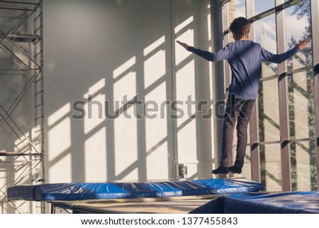 Boy jumps and flies on a trampoline in a fitness room. Sport