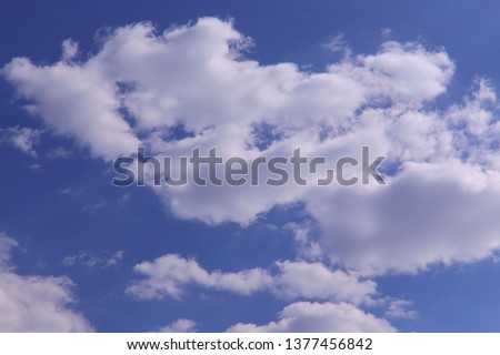 Blue sky background with white clouds on a sunny day. Nature concept. Horizontal, plenty of space for text.