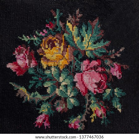 Cross-stitch handmade embroidery. The bouquet of roses and leafs on black background. Decorative element for design.