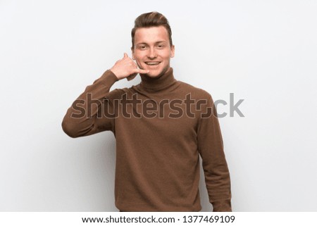 Blonde man over isolated white wall making phone gesture. Call me back sign