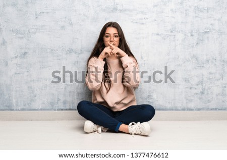 Teenager student girl studying in a table showing a sign of silence gesture