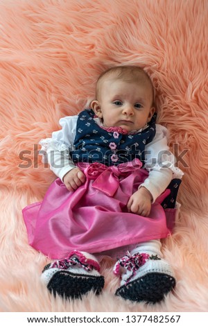The picture shows a newborn baby girl in a dirndl