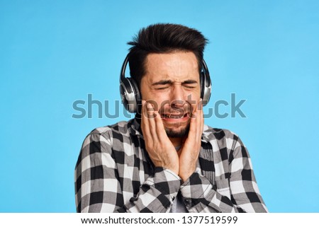 man in headphones with closed eyes on a blue background emotions sadness sad                              
