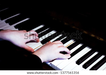 Child's hands on piano keyboard. Kid plays and practices piano at home. Black and white music background. Classical and jazz pianist. Piano lessons for kids. 