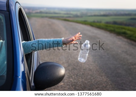 Do not pollute nature with plastic waste!  Driver throwing away plastic bottle from car window. Environmental conservation Royalty-Free Stock Photo #1377561680