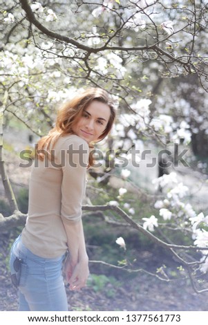 Young woman in blooming magnolia garden