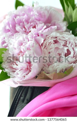 Light pink peony bouquet wrapped in tissue paper in tote bag with copy space