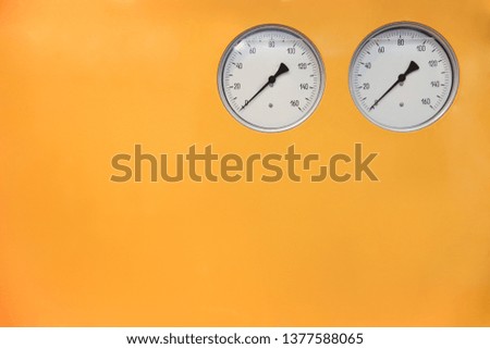 yellow background with two round dials in the top corner. pressure meters on yellow background. the dials of pressure gauges liquid