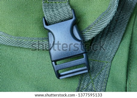 black plastic carbine with a harness on the green matter of the backpack