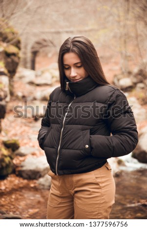 Portrait of brunette girl with black coat, bowling pins and brown pants in forest in autumn in Santa Fe del Montseny, Catalonia, Spain