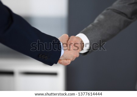 Business people shaking hands at meeting or negotiation in modern office, close-up. Teamwork, partnership and handshake concept