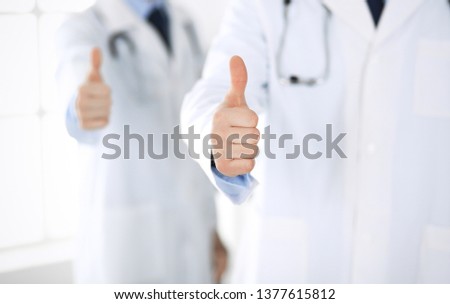 Doctor man standing straight with colleague and showing thumbs up. Group of doctors. Perfect medical service in clinic. Medicine and healthcare concepts