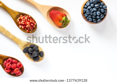 Top down view of spoons filled with berries and a bowl with blueberries. healthy antioxidant concept. Royalty-Free Stock Photo #1377639128
