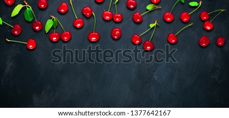 Beautiful Panoramic food background. Frame of red ripe cherries with green leaves on black background. Creative template with Copy Space for design. Top view. Flat lay.