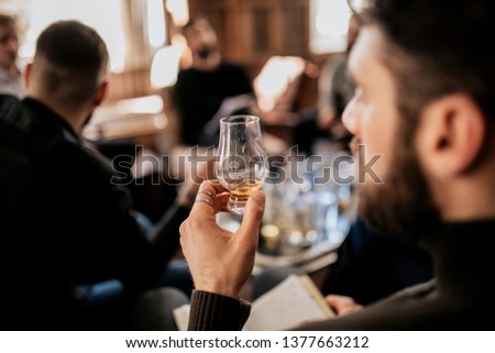 A close up shot of a young european man tasting Japanese whisky. Concept of fine alcohol. Master class and degustation of whisky.  Royalty-Free Stock Photo #1377663212