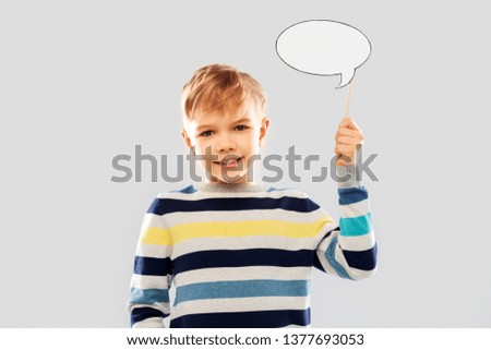 party props, photo booth and communication concept - smiling little boy holding blank speech bubble over grey background Royalty-Free Stock Photo #1377693053