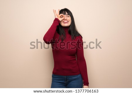 Young woman with red turtleneck makes funny and crazy face emotion