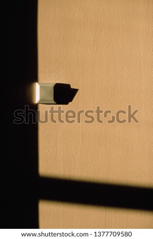 A geometric minimalism with a beige wall, a square shadow and a small light switch