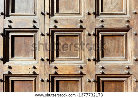 Brown wooden door abstract studded with iron nails or bolts