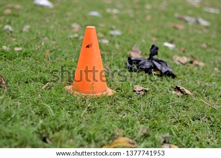 Orange color plastic cone on green grass field