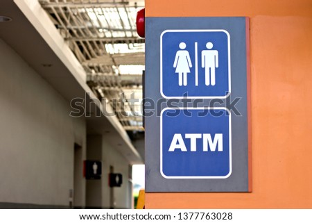 Public restroom and ATM sign on the orange wall.