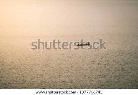 A man fishing on small boat floating in a lake with yellow sunlight in the morning.