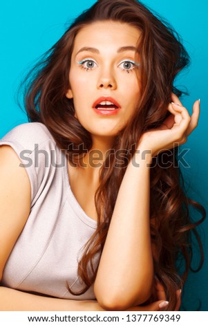 young pretty teenage modern girl posing emotional happy on blue background, lifestyle people concept
