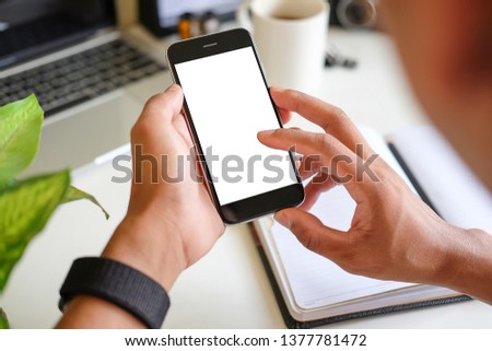 Cropped shot view of man hands holding smart phone with blank copy space screen for your text message or information content, female reading text message on cell telephone during in urban setting. 