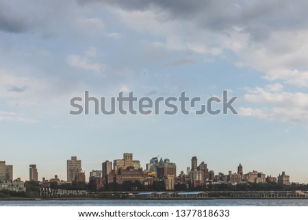 Skyline of Brooklyn under sky and clouds at dusk, viewed from Manhattan, New York, USA