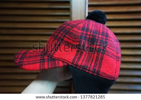 Close up hand holding red and black buffalo check winter hat