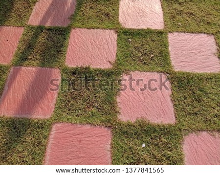 Pink concrete square background on green grass