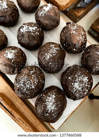 Chocolate Truffle Balls with Coconut Powder on Paper with Wooden Tray.
