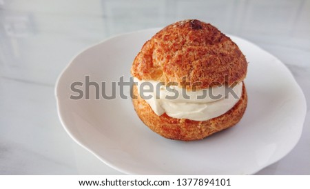 Choux pastry cream puff in white plate on marble table. Soft and mild dessert best refreshing dish for summer