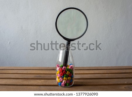 Wooden alphabet in a glass jar and magnifier on wooden background. Concept for search engine optimization or key wording.