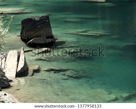 Isolated rock in the turquoise waters of Lake Cauma, Grisons, Swiss Alps