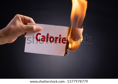 Woman hand holding a burning piece of paper with the word calories. Healthcare concept. Royalty-Free Stock Photo #1377978779