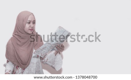 Portait of asian muslim woman wearing head scarf or hijab with luggage and suit case holding and reading a map get ready for the trip - image