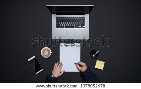 Businessman hands writing on white paper with office supplies . Flat lay and top view with copy space on black background .business desk  lifestyle concept.