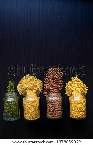 collection of cereal and carbohydrate of food chart,food background is black wooden ,the image consist of pigeon peas,yellow split peas,brown chickpeas and green gram.