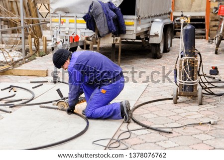 pictured in the photo a man cuts metal squares with a grinder
