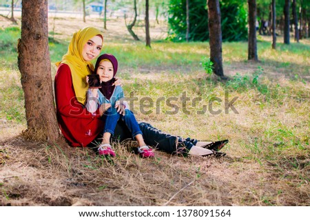 Muslim Indonesian family mom and child concept. Young Asian Muslim Mother and her daughter child girl smiling hugging and kissing together 