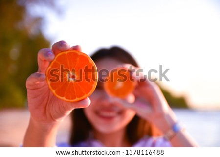 woman holding orange slice at beach sea background 